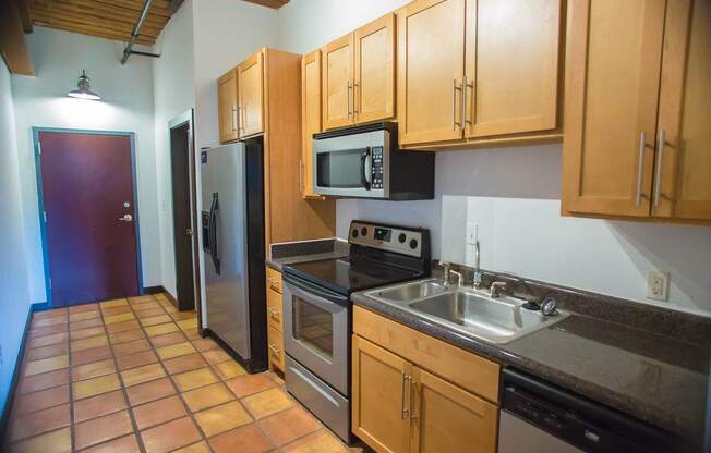 A kitchen with brown cabinets and a black fridge.