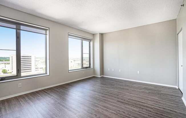 an empty living room with three large windows