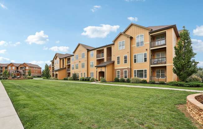 the view of an apartment building with a green lawn