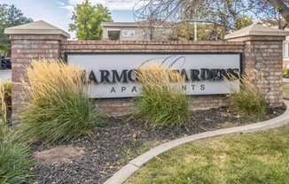 a sign apartments in front of a brick wall with tall grass