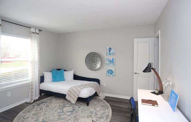 A bedroom with a bed, a rug, a lamp, and pictures on the wall.