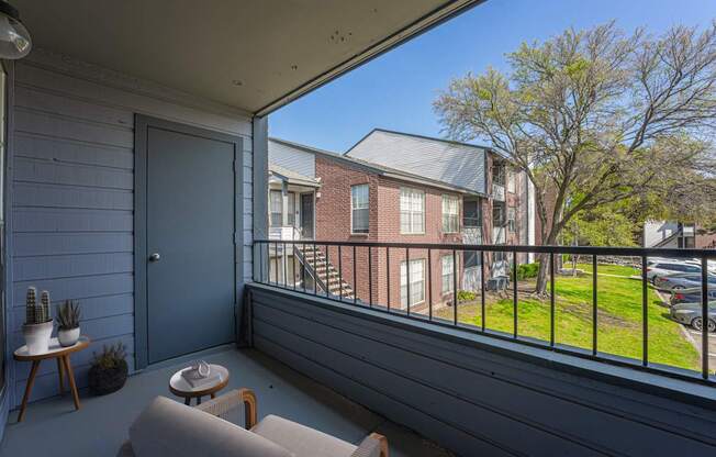 A balcony with a grey floor and a blue door.