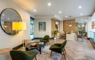 A modern living room with a green chair and a round mirror on the wall.