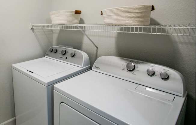 Two white front loading washing machines in a laundry room.