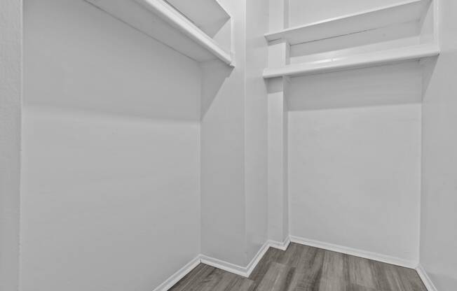 an empty room with white walls and wooden floors and a white closet with a window