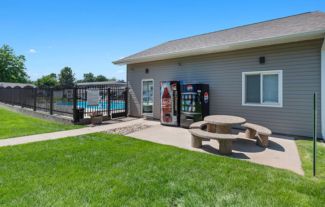 a picnic table in front of a house with a gas station