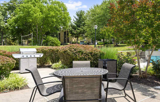 a patio with a table and chairs and a grill