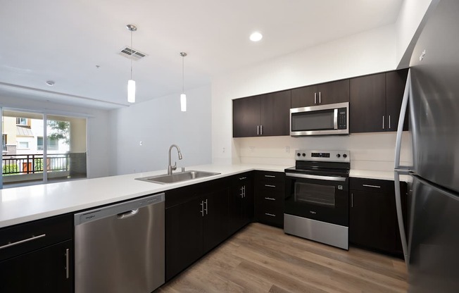 A modern kitchen with black cabinets and stainless steel appliances.