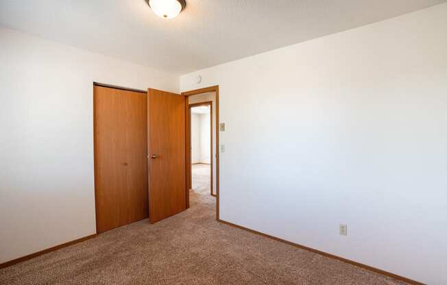 a bedroom with a carpeted floor and a door to a closet. Fargo, ND Westview Towers Apartments