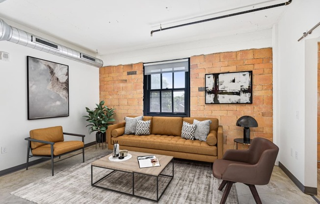 a living room with a couch and a coffee table and a brick wall