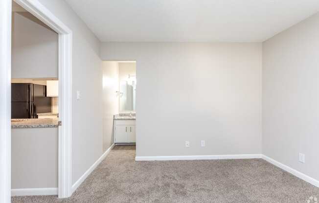 an empty living room with carpet and a kitchen