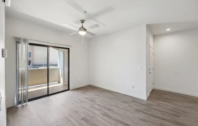 A room with a ceiling fan and sliding glass doors.