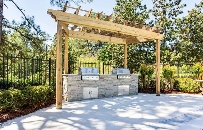 A wooden pergola is over a stone fireplace.