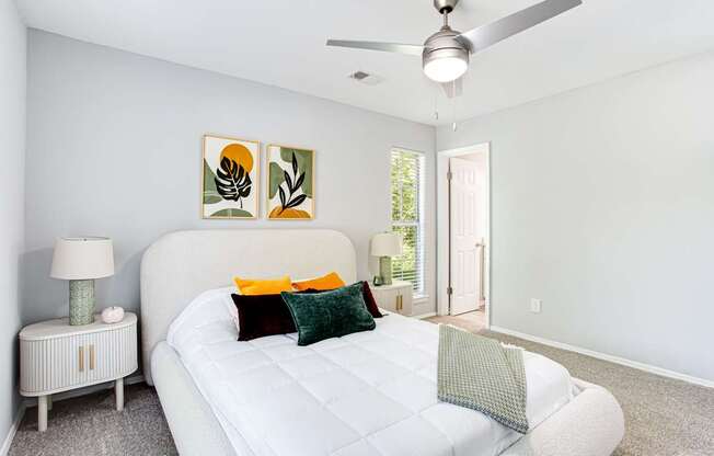A bedroom with a white bed and a ceiling fan.