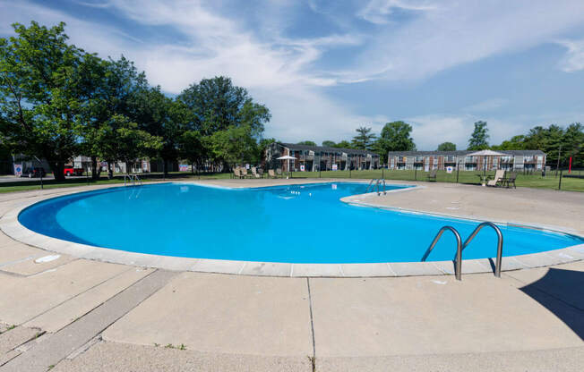 a swimming pool with trees and apartments in the background