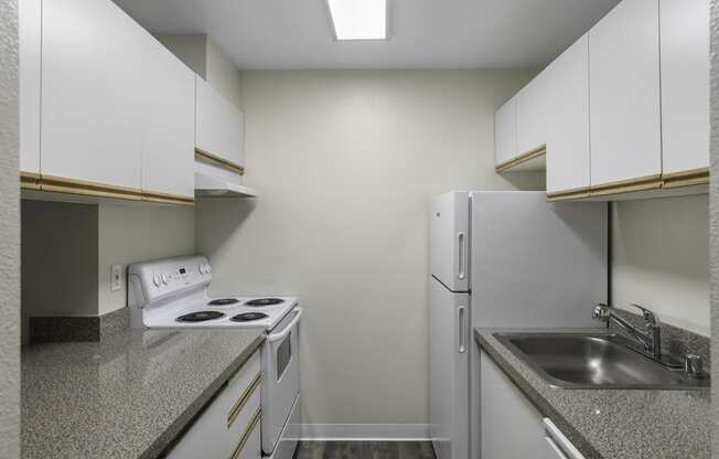 Spacious kitchen with white appliances, white cabinets, and plank flooring at West Mall Place Apartment Homes, Everett