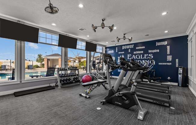 Resident Fitness Center with natural light and a wall of windows overlooking the pool at Eagles Landing Apartments, Ammon, ID