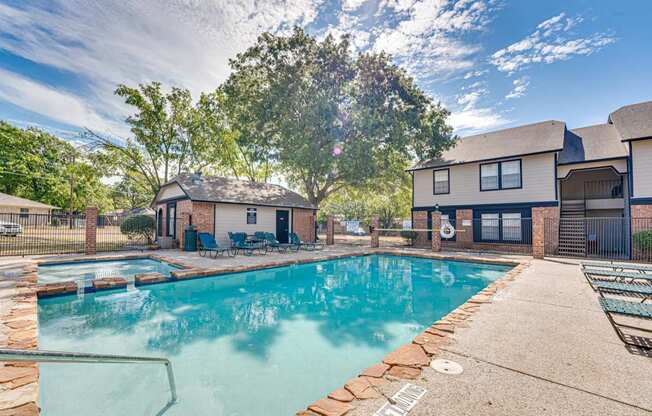 A swimming pool surrounded by a concrete patio and a black fence.