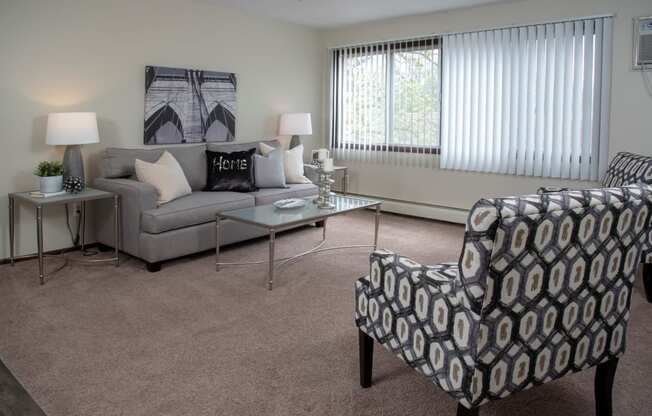 Bright Carpeted Living Room with Large Windows at 600 10th Ave Apartments