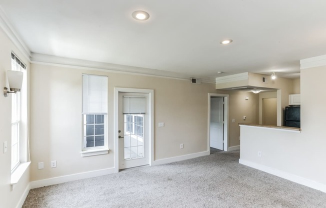 an empty living room with white walls and doors and a carpet floor