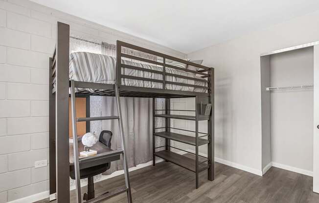 A room with a bunk bed and a desk.