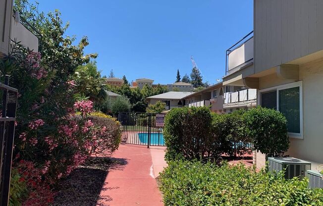 a walkway between two buildings with a swimming pool