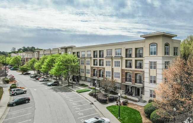 A street view of a row of apartment buildings with cars parked on the side of the road.