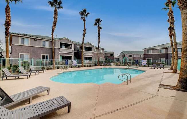 A pool surrounded by palm trees and lounge chairs.