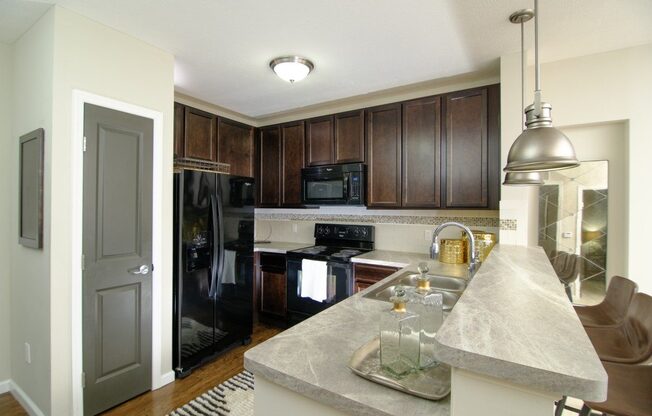 A kitchen with a granite counter top and a black refrigerator.
