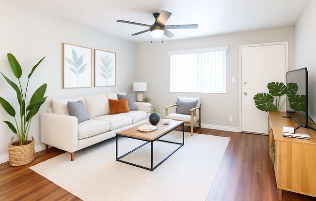 A living room with a white couch, a coffee table, and a ceiling fan.
