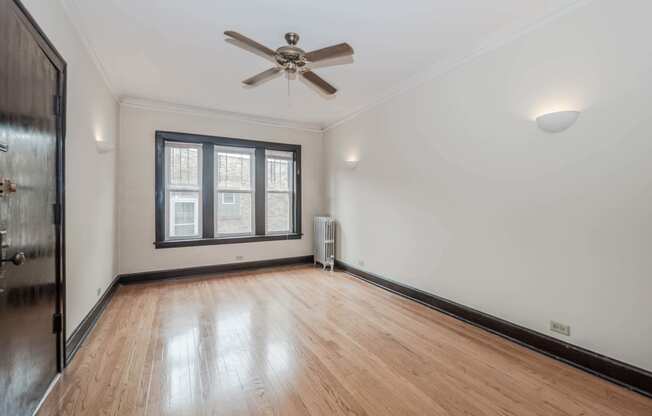 an empty room with hardwood floors and a ceiling fan