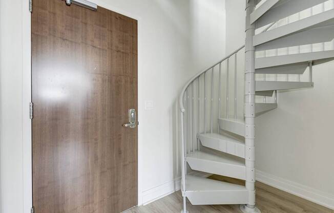 A white spiral staircase with a wooden door.