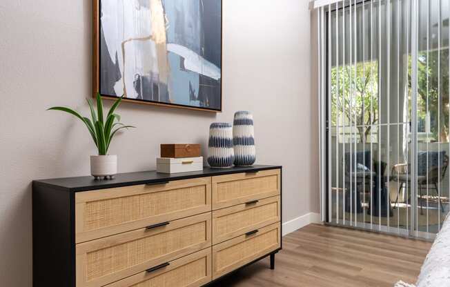 a living room with a dresser and a window with a sliding glass door