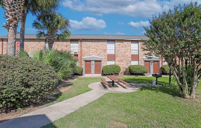 A brick apartment building with a red door and a barbeque area in front of it at Magnolia Apartments in Shreveport, LA
