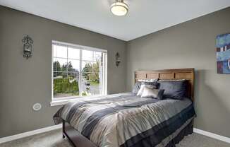 A bedroom with a bed, a window, and a painting on the wall.