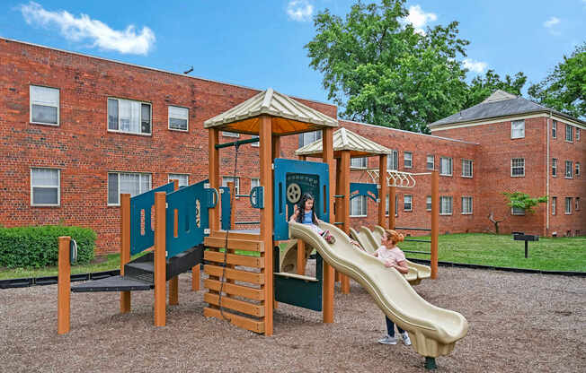 a child playing on a playground in front of a brick building at Hamilton Manor Apartments, Hyattsville, Maryland