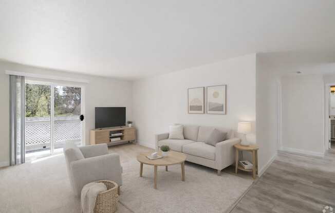 A living room with a white couch, a wooden coffee table, and a television.
