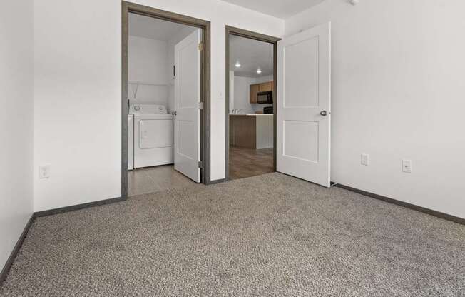 A carpeted room with a white door and a brown door.