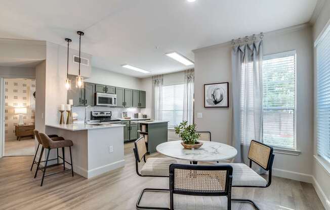 A kitchen with a table and chairs in front of a window.