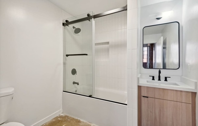 A bathroom with a toilet, sink, and a glass shower stall.