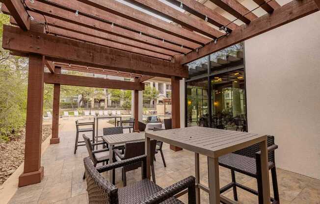 A patio with a table and chairs under a wooden pergola.