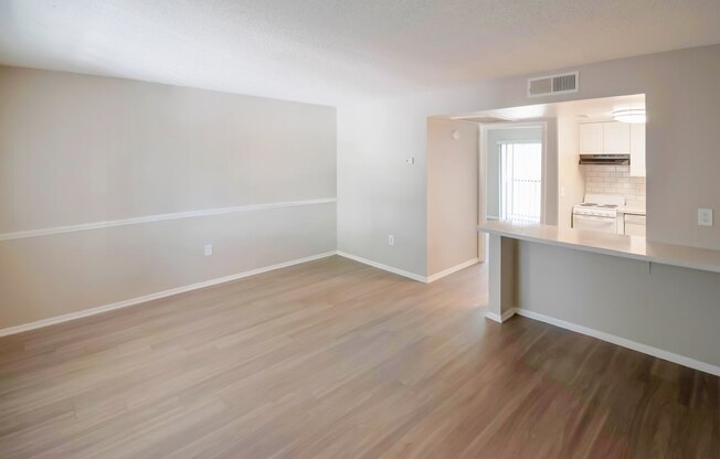 an empty living room and kitchen with wood flooring