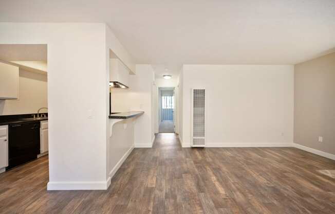 the living room and kitchen of an apartment with wood flooring