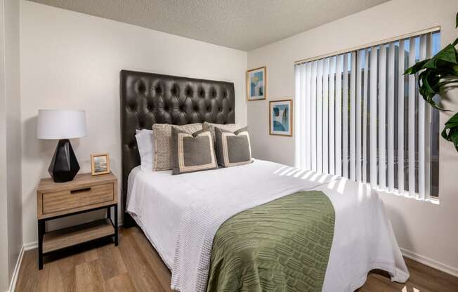 A bedroom with a large bed and a nightstand with a lamp.