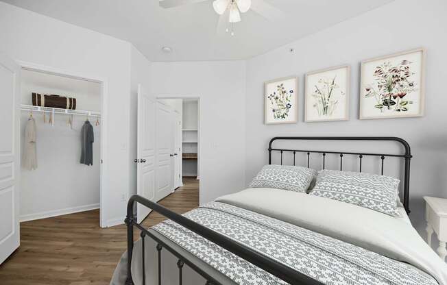 A bedroom with a bed, a ceiling fan, and three framed pictures on the wall.