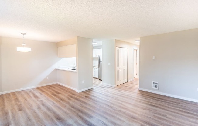 an empty living room and kitchen with a wood floor