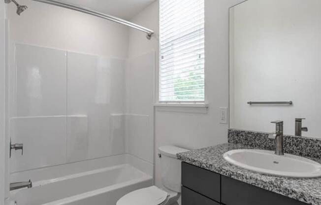 A white bathroom with a toilet, sink, and bathtub.
