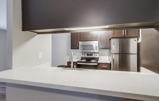 A modern kitchen with stainless steel appliances and a flat screen TV mounted above the island.