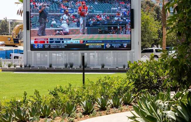 A large outdoor television screen is displaying a baseball game. at Elements Apartments*, Irvine, CA