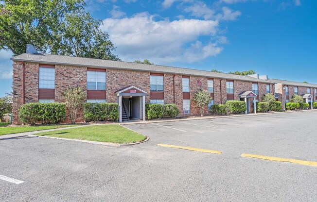 A brick apartment building with a parking lot in front at Magnolia Apartments in Shreveport, LA